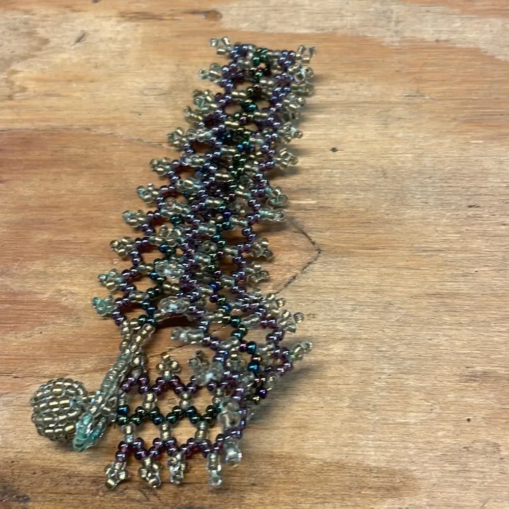 Woman’s beaded bracelet. Colors are gold,green and purple